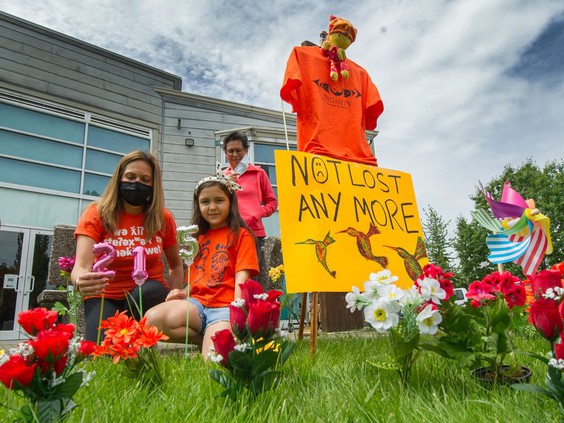 Photo of Musqueam members placing flowers and balloons at a memorial for the 215 children whose remains were found at Kamloops Indian Residential School.