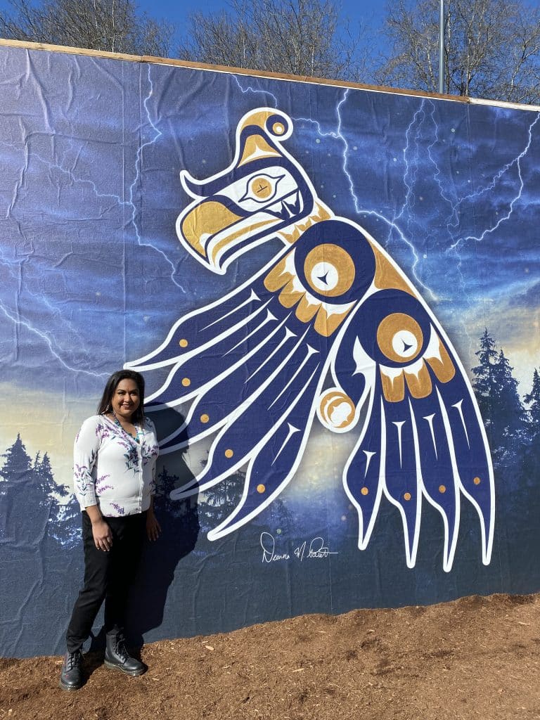Deanna Point in front of her artwork for the UBC Thunderbirds.